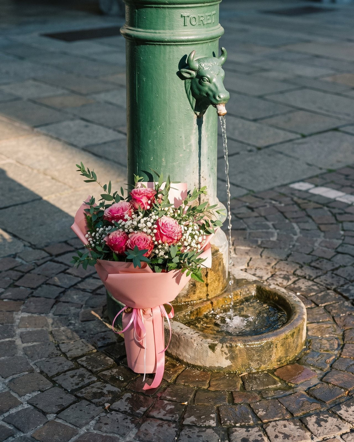Mazzo di rose rosa e gypsophila per una nascita appoggiato a una fontanella toret di Torino
