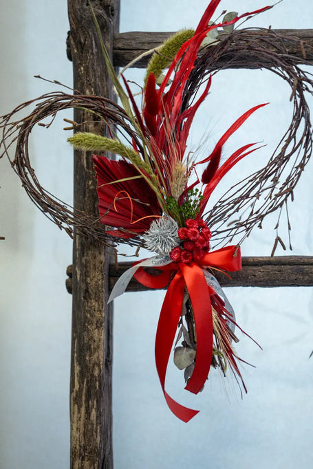 Composizione a cuore con fiori secchi e nastro rosso