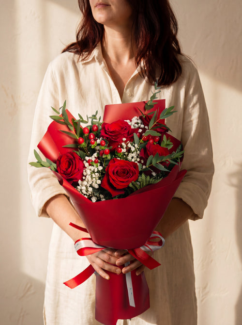 Roseto - bouquet di rose rosse, hypericum e gypsophila, tenuto in mano