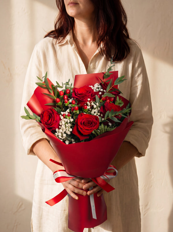 Roseto - bouquet di rose rosse, hypericum e gypsophila, tenuto in mano