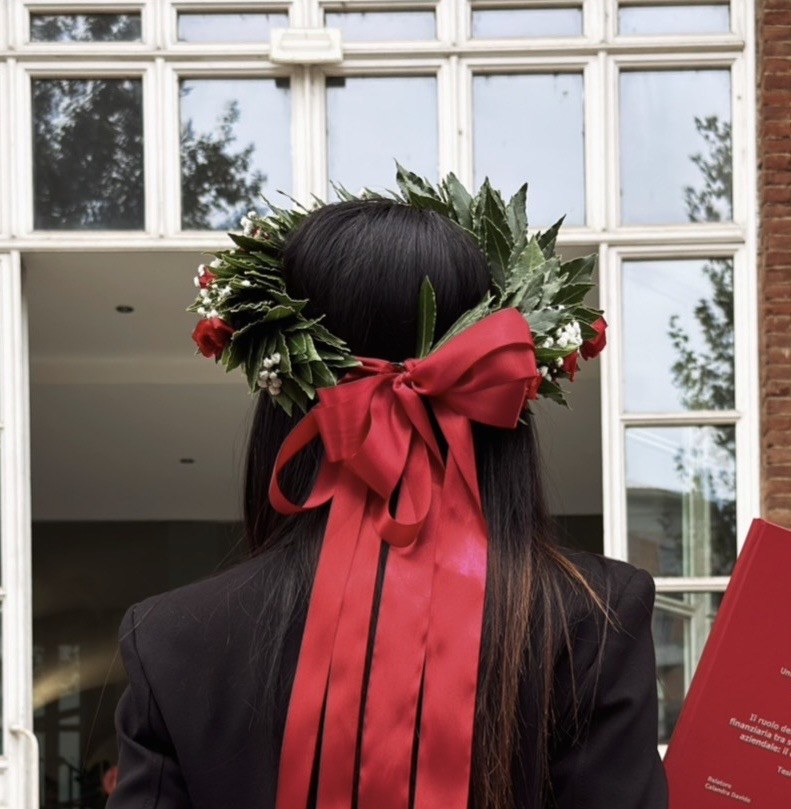 Corona di laurea Emozioni con alloro, roselline rosse e fiocco rosso, foto della cliente Angela